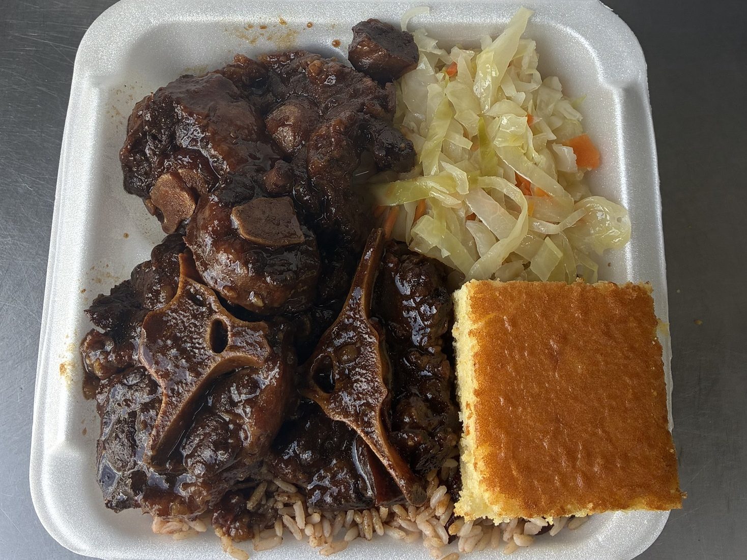 Oxtail with rice and peas, steamed cabbage and cornbread
