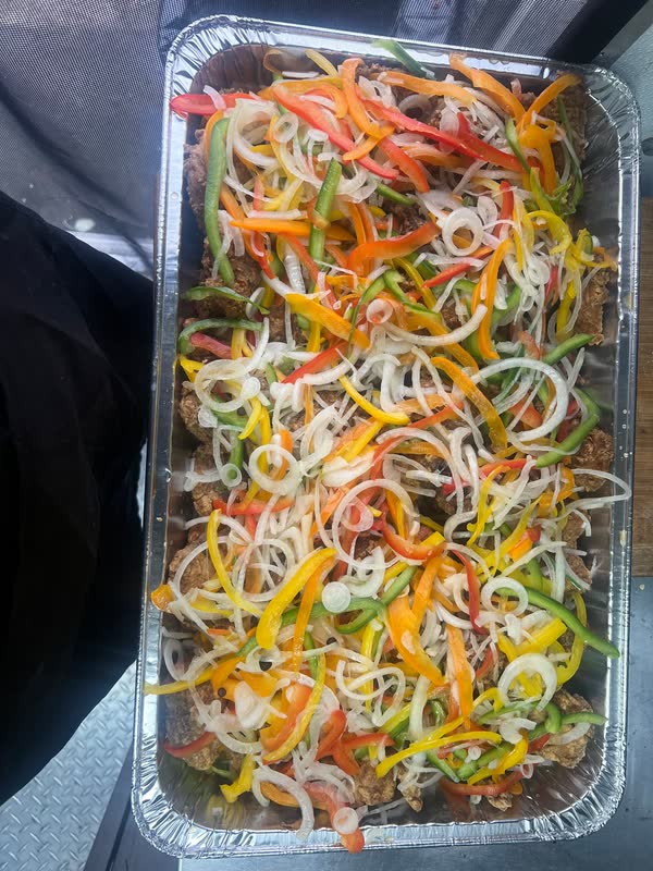 A tray of escovitch fish under sliced peppers and onions